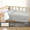 A quilted blanket is laid out on a child's bed, with a teddy bear and pillow visible. Produktbild-Vorschau