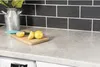 A kitchen countertop with a roll of d-c-fix® self-adhesive film in Avellino Stone pattern, along with lemons and a metal pitcher. Podgląd zdjęcia produktu