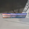 A TV screen mounted on a wall, displaying a landscape image. Produktbild-Vorschau
