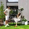 A couple relaxing in a hanging chair in a garden setting. Produktbild-Vorschau