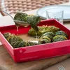 A close-up shot of food being prepared in a red baking dish. Produktbild-Vorschau
