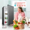 A woman is sitting on the floor next to an open refrigerator, surrounded by groceries. The refrigerator is filled with food items, and a paper bag overflowing with fresh produce and bread is placed in front of her. A graphic overlay displays a thermometer  Produktbild-Vorschau