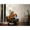 A woman and a child are sitting in a chair and reading a book together. Anteprima dell’immagine prodotto