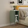 A mint green nightstand with a closed door and open compartment, placed next to a bed with yellow headboard and pillows. A wall lamp is mounted above the nightstand. Anteprima dell’immagine prodotto
