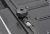 Close-up of a black plastic knob and a metal screw on a dark gray textured surface, likely part of a roof box or similar cargo carrier. Náhľad obrázku produktu