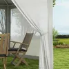 A view of a gazebo with chairs and a table set up on a grassy lawn, with trees and hills in the background. Produktbild-Vorschau