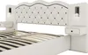 A close-up view of a white upholstered bed frame with integrated nightstands and lighting. Voir les images du produit
