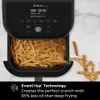 An air fryer filled with french fries, with some fries spilled out next to it. Produktbild-Vorschau