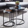 Two nesting round side tables with marble-look tops and black metal frames are placed on a rug in front of a sectional sofa. Anteprima dell’immagine prodotto