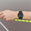 A person's wrist wearing a black watch, holding a rope. Podgląd zdjęcia produktu