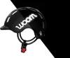 A black woom helmet is shown against a split black and white background. Produktbild-Vorschau