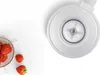A close-up, top-down view of a white kitchen appliance part, with a small colander of strawberries to the left. Produktbild-Vorschau