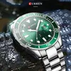 A close-up shot of a men's wristwatch with a green dial and silver band, set against a dark, wet, rocky background. Produktbild-Vorschau