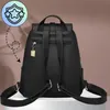 The back view of a black leather backpack is shown against a light brown background. Voir les images du produit