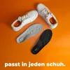 Zwei weiße Sneaker mit einer hellgrauen und einer schwarzen Step Ease-Einlage, Text lautet 'passt in jeden Schuh' Produktbild-Vorschau