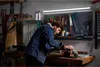 A man is working on a wooden workbench in a garage or workshop. Anteprima dell’immagine prodotto