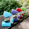 Four colorful children's microscopes are lined up on a wooden surface with a blurred green background of foliage. Produktbild-Vorschau
