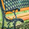 Close-up of a garden bench with ornate metalwork and wooden slats. Podgląd zdjęcia produktu