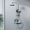 A modern chrome shower system with a rainfall showerhead, handheld shower, glass shelf, and digital display, mounted on a gray wall. Anteprima dell’immagine prodotto