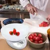 A chef is preparing food in a kitchen, with a digital scale, tomatoes, and bowls on a counter. Voir les images du produit