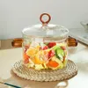 A glass pot filled with vegetables sits on a woven placemat. Produktbild-Vorschau