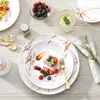 A beautifully set table with marble-patterned plates, cutlery, and a dessert with berries. Produktbild-Vorschau