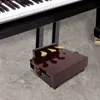 A close-up view of a piano pedal extender bank placed on a marble floor in front of a piano. Náhled obrázku produktu