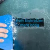 A hand is using a blue ice scraper to clear ice and snow from a car windshield. Text is overlaid on the cleared area. Anteprima dell’immagine prodotto