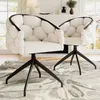 Two beige upholstered chairs with black metal legs are placed on a patterned rug in a living room setting, with a fireplace and window in the background. Produktbild-Vorschau