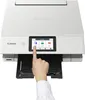 A hand is shown touching the screen of a white Canon PIXMA TS8751 printer. Podgląd zdjęcia produktu