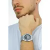 A man wearing a white t-shirt and a silver watch on his left wrist, with his hand resting on his chin. Náhled obrázku produktu