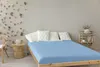 A bedroom scene with a bed, chair, and shelf. Produktbild-Vorschau