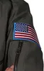 A close-up of a gray pilot jumpsuit sleeve with an American flag patch and a zipper pocket. Produktbild-Vorschau