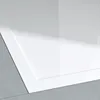 A close-up view of a white shower tray placed on a gray tiled floor. Produktbild-Vorschau