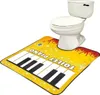 A toilet sits on a yellow piano-themed mat. Anteprima dell’immagine prodotto