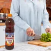 A person is preparing food in a kitchen, with a bottle of Melfor Original vinegar prominently displayed on the counter. Produktbild-Vorschau