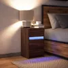 A bedside table with a lamp and books next to a bed. Náhled obrázku produktu