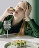 A young woman is eating sushi and drinking water. Produktbild-Vorschau