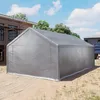 A large, gray, tent-like structure is set up on a dirt and grass area. A building under construction with scaffolding is visible in the background. Voir les images du produit