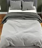A close-up view of a bed with gray bedding and pillows. Náhled obrázku produktu