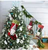 Christmas tree decorated with ornaments and stockings hanging on a staircase. Náhľad obrázku produktu