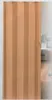 A closed folding door in a room with a kitchen in the background. Produktbild-Vorschau
