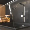 A modern kitchen sink with a faucet dispensing water, surrounded by wooden bowls and glass jars of nuts. Produktbild-Vorschau
