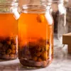 Two glass jars filled with an orange liquid and berries are on a marble surface. Podgląd zdjęcia produktu