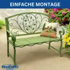 A green metal garden bench with a decorative backrest, placed outdoors with flowers in the background. Podgląd zdjęcia produktu
