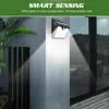 A solar-powered wall light with a motion sensor is mounted on a textured wall, illuminating the surrounding area. Voir les images du produit