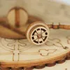 A close-up view of a wooden 3D puzzle gramophone component, focusing on a small wheel with intricate detailing. Podgląd zdjęcia produktu