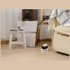 A small robot is on the floor next to a couch in a room. Náhled obrázku produktu