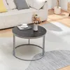 A round coffee table with a marble-like black top and silver legs is placed on a rug in a living room setting, next to a sofa. Produktbild-Vorschau