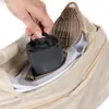 A hand is placing a portable electric pump into a beige storage bag. Produktbild-Vorschau